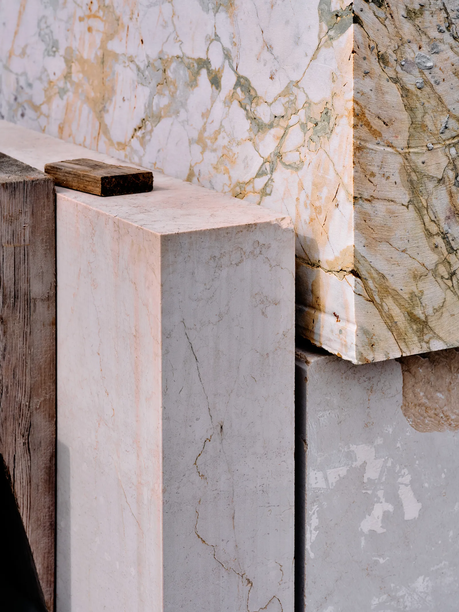 Close-up of marble slabs in varying color and veining, stacked edge to edge and separated by a thin wooden shim.